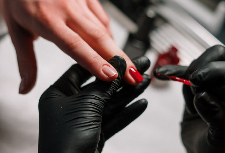 Nail tech putting on your own red Liberation Nails polish at the nail salon.