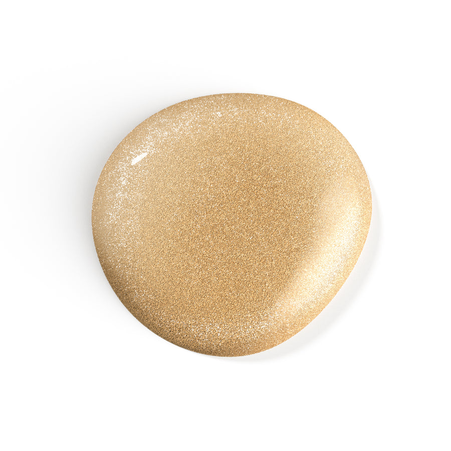 A droplet of Liberation Nails shimmery gold nail polish, Gilded Mystic