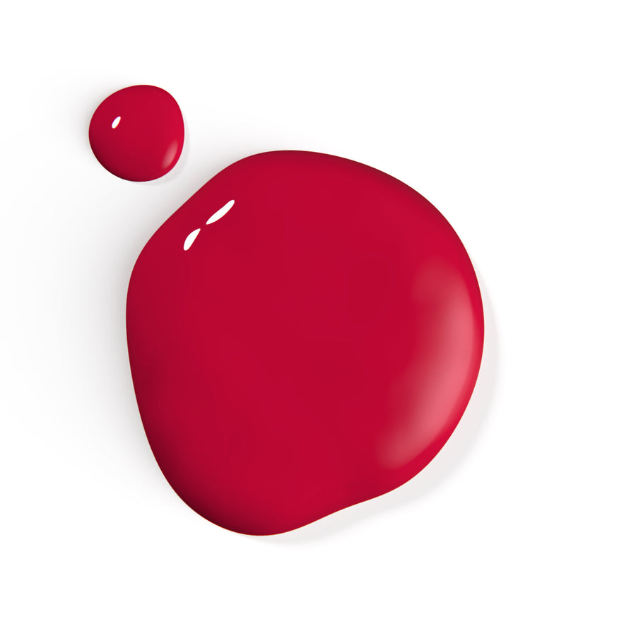 A droplet of Liberation Nails nail polish in a cool-toned red color, Looker.